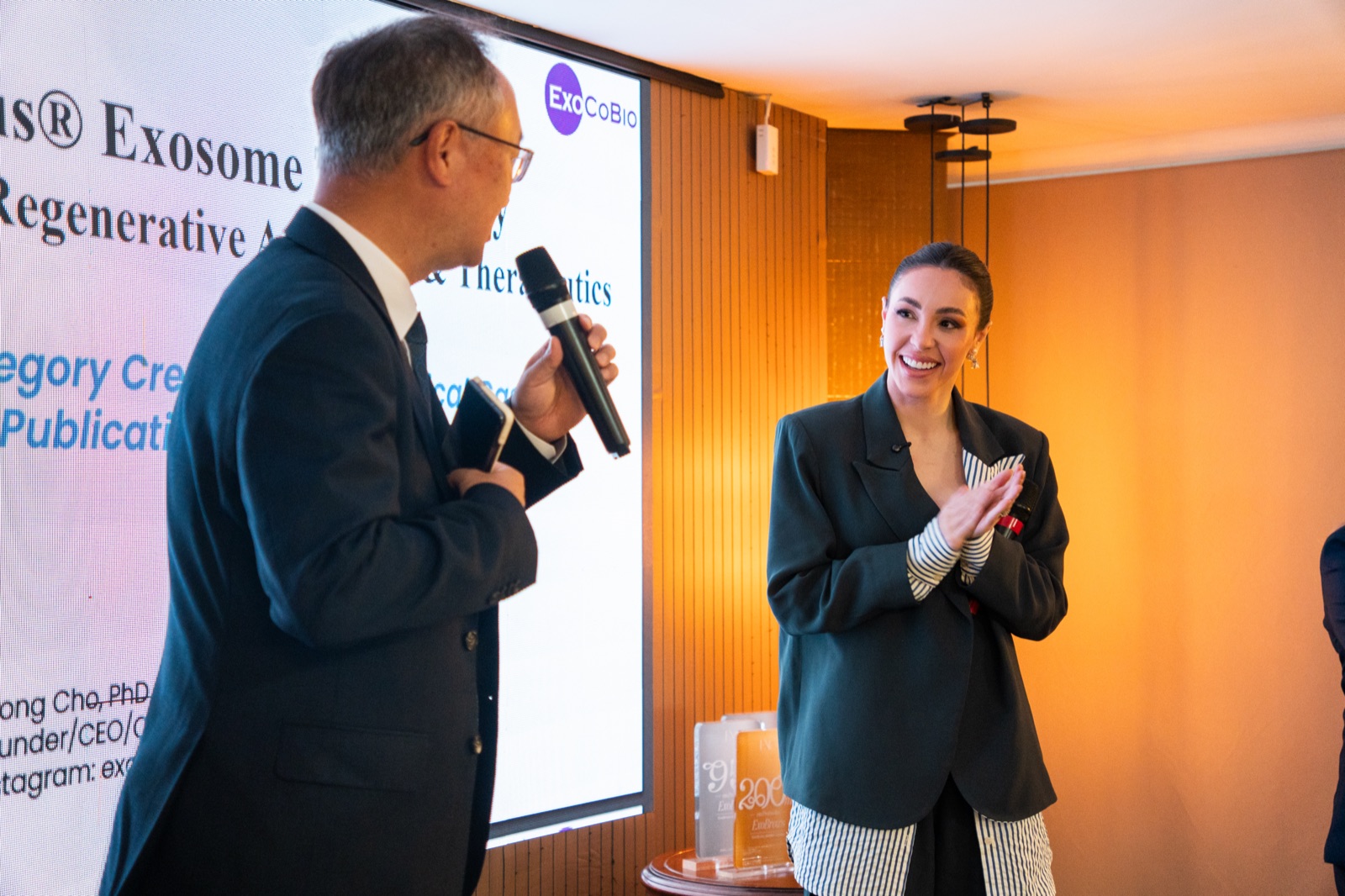 Dr. Byong Seung Cho lecturing while Brenda Terra Zimmer applauds, Brazil Summit